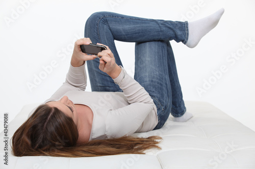 Foto: Girl laying on back watching film on her mobile Girl laying on back watching film on her mobile