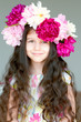 Adorable little girl with wreath from peony flowers in studio