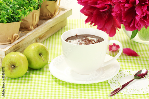 Foto: cup hot chocolate, apples and flowers on table in cafe cup hot chocolate, apples and flowers on table in cafe
