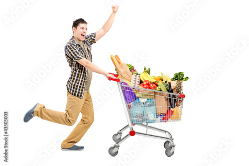 Photo: Full length portrait of a happy man pushing a shopping cart Full length portrait of a happy man pushing a shopping cart