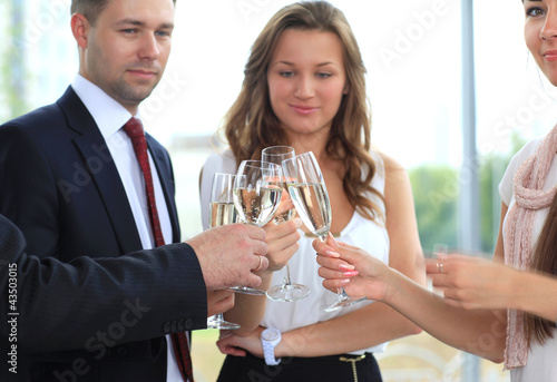 Photo: Business people raising toast with champagne at office Business people raising toast with champagne at office