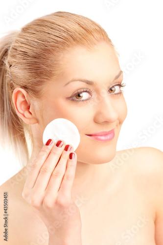 Foto: Young blond woman cleaning her face with cotton pad Young blond woman cleaning her face with cotton pad