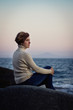 girl sitting on a rock by the sea at sunset