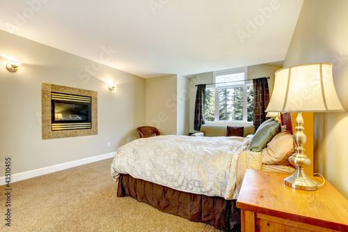 Photo: Large bedroom with fireplace and nightstand with lamp. Large bedroom with fireplace and nightstand with lamp.