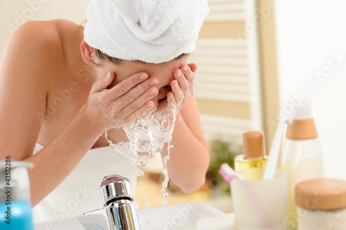 Photo: Woman splashing face with water in bathroom Woman splashing face with water in bathroom