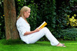 Frau liest Buch im Park