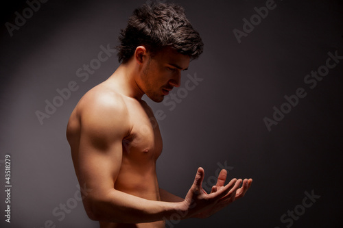 Photo: young muscular man with a bare chested on black. young muscular man with a bare chested on black.