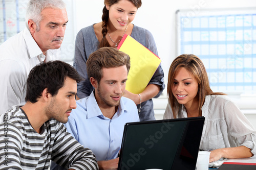 Foto: Informal team of people sitting round a laptop computer Informal team of people sitting round a laptop computer
