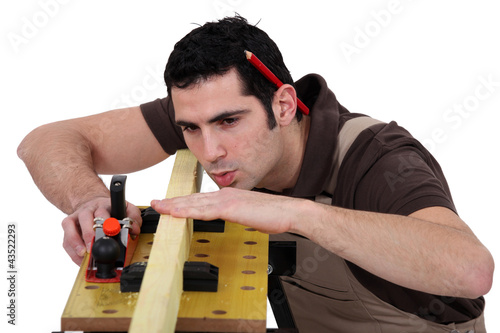 Foto: Man smoothing plank of wood with plane Man smoothing plank of wood with plane