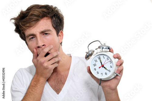 Photo: Yawning man holding alarm clock Yawning man holding alarm clock