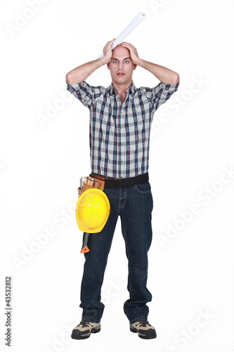 Photo: Construction worker holding his head in horror Construction worker holding his head in horror