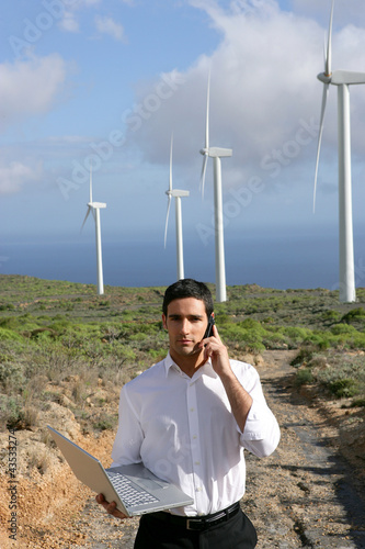 Photo: Man with laptop stood by wind farm Man with laptop stood by wind farm