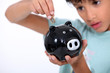 boy putting a coin into a money box