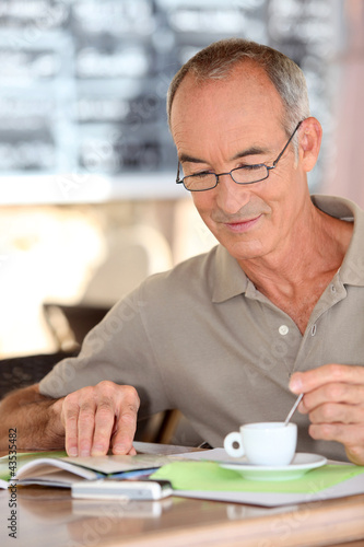 Photo: Old man drinking coffee and reading Old man drinking coffee and reading