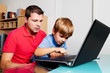 Mann und Kind mit Laptop Computer in Wohnung.