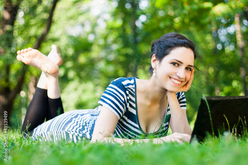 Photo: Beautiful young woman using her laptop outdoors Beautiful young woman using her laptop outdoors