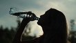 Silhouette of young woman drinking water over sunset