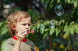 Little cute boy blowing a bubbles outdoors on a sunny day