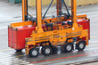 Foto: Large loader drives on wet asphalt and carries red container Large loader drives on wet asphalt and carries red container