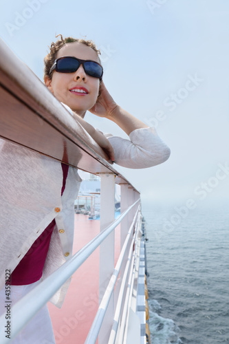 Foto: Beautiful woman wearing sunglasses stands on board of ship Beautiful woman wearing sunglasses stands on board of ship