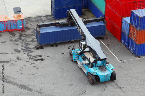 Photo: Small crane lifts large weight blue container, view from above Small crane lifts large weight blue container, view from above