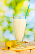 Banana milk shake on wooden table on bright background