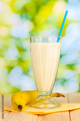 Photo: Banana milk shake on wooden table on bright background Banana milk shake on wooden table on bright background