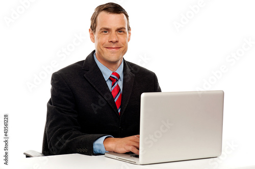 Photo: Male executive at work desk operating laptop Male executive at work desk operating laptop
