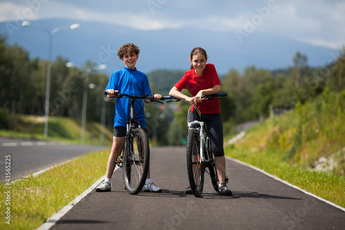 Photo: Girl and boy biking Girl and boy biking