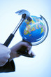 Portrait of a hand holding a hammer trying to break a globe