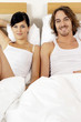 A couple sitting together on two single beds