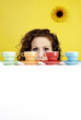 Woman hiding behind four colourful cups