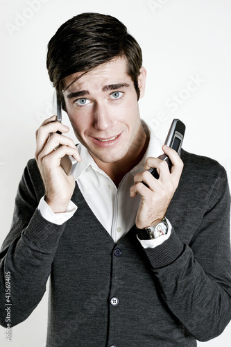 Photo: Man answering two phone calls Man answering two phone calls