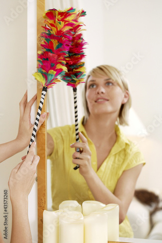 Photo: Woman using a feather duster to clean the mirror Woman using a feather duster to clean the mirror