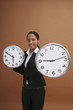 Businesswoman holding clocks of different sizes