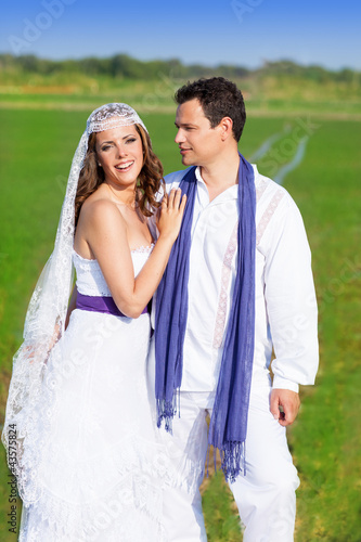 Photo: Couple in wedding day hug in green meadow Couple in wedding day hug in green meadow