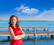Photo: Brunette woman dress in red smiling relaxed on a lake Brunette woman dress in red smiling relaxed on a lake