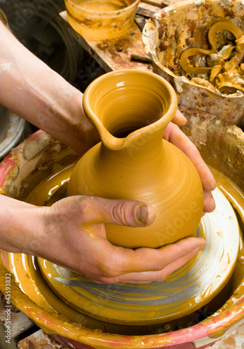 Photo: hands of a potter, creating an earthen jar on the circle hands of a potter, creating an earthen jar on the circle