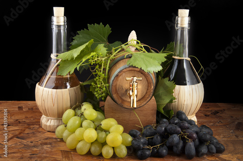 Photo: In oak casks with vines and grapes white and black In oak casks with vines and grapes white and black