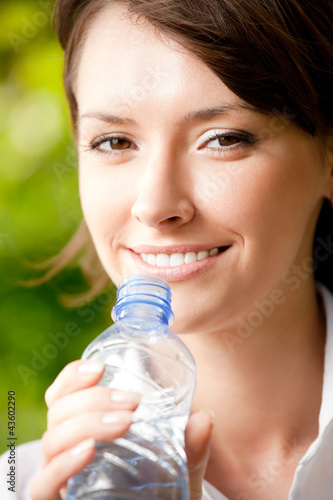 Photo: Young woman with bottle of water outdoors Young woman with bottle of water outdoors