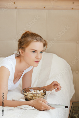 Photo: happy teenage girl with TV remote and popcorn happy teenage girl with TV remote and popcorn
