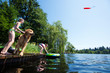 Children playing fetch with their golden retriever dog on a lake