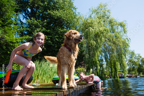 Photo: children playing with their Golden Retriever dog on a lake children playing with their Golden Retriever dog on a lake
