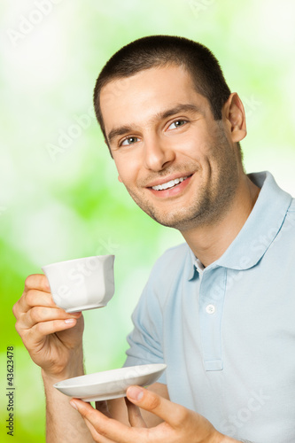 Photo: Happy smiling man drinking coffee, outdoors Happy smiling man drinking coffee, outdoors