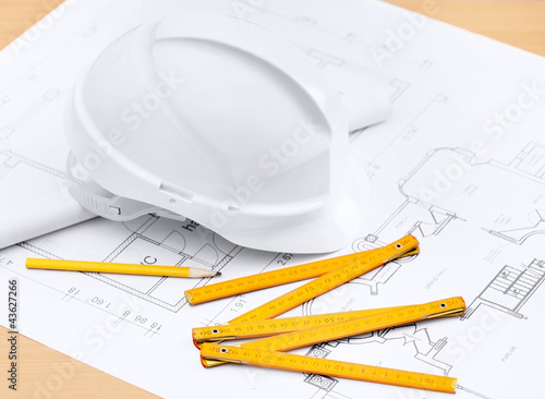 Photo: White hard hat near working drawings White hard hat near working drawings