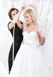 Shop assistant helps to the bride to fix the wedding veil