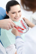 Dentist and his assistant teach the patient how to clean teeth