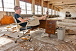 Working on a laptop at a desk inside an abandoned factory.