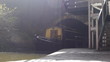 Backlit tracking shot of a barge coming out of a tunnel.