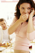 A woman whispering on the hand phone as her husband watching suspiciously